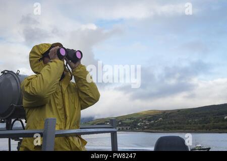 FASLANE, Scotland (Sept. 28, 2017) Logistics Specialist 3rd Class Pedro Wacdagan, assigned to the Arleigh Burke-class guided-missile destroyer USS Mitscher (DDG 57), stands watch on the ship's bridge wing during sea and anchor detail, Sept. 28, 2017.  Mitscher, homeported in Norfolk, is conducting naval operations in the U.S. 6th Fleet area of operations in support of U.S. national security interests in Europe. Stock Photo