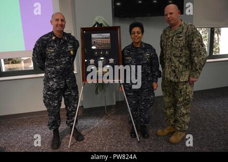 NAVAL SUPPORT ACTIVITY NAPLES, Italy (Oct. 2, 2017) Adm. Michelle J. Howard, commander, U.S. Naval Forces Europe-Africa and commander, Allied Joint Forces Command Naples, center, is presented a gift by U.S. 6th Fleet Command Master Chief Richard O’Rawe, left, and Senior Chief Builder Bruce Sims Oct. 2, 2017.  U.S. Naval Forces Europe-Africa, headquartered in Naples, Italy, oversees joint and naval operations, often in concert with allied, joint, and interagency partners, to enable enduring relationships and increase vigilance and resilience in Europe and Africa. Stock Photo