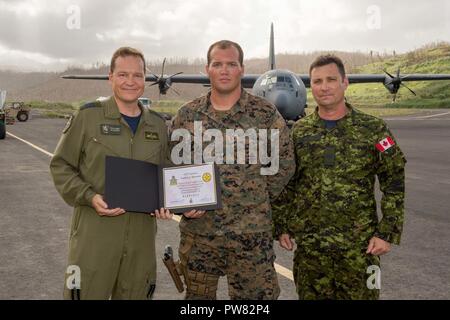 U.S. Marine Cpl. Michael A. Fleenor, a heavy equipment operator with Joint Task Force - Leeward Islands, poses for a photo with Royal Canadian Air Force Lt. Col. Paul-Éric Gilbert, left, the Royal Canadian Air Task Force commander, and Royal Canadian Air Force Master Warrant Officer Joel Langley, the ATF chief, after an award ceremony at Charles-Douglas Airport in Melville Hall, Dominica, Oct. 2, 2017.   Fleenor was presented with a certificate of appreciation for his efforts in supporting both U.S. and foreign military efforts during hurricane relief operations in Dominica. At the request of  Stock Photo