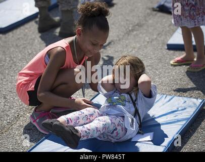 A young wingman helps a fellow deployer with physical training during Operation Hero Sept. 30 at Eglin Air Force Base, Fla. More than 470 kids participated in the event set up to show the process their parents go through before they leave home. They participated in three phases. The first included a deployment line for dog tag issue and 'immunizations.' After a brief from the commander they moved on to Phase Two activities set up by base organizations. The last phase included a welcome home lunch. Stock Photo