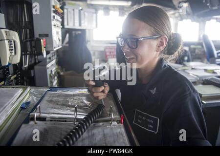 5TH FLEET AREA OF OPERATIONS (Sept. 21, 2017) Boatswain’s Mate 3rd Class Ashley Frost, a native of Kansas City, Missouri, assigned to the deck department aboard the amphibious dock landing ship USS Pearl Harbor (LSD 52), makes an announcement over the ship’s 1MC while standing watch in the bridge. Pearl Harbor is part of the America Amphibious Ready Group (ARG) and, with the embarked 15th Marine Expeditionary Unit (MEU), is deployed in support of maritime security operations and theater security cooperation efforts in the U.S. 5th Fleet area of operations. Stock Photo