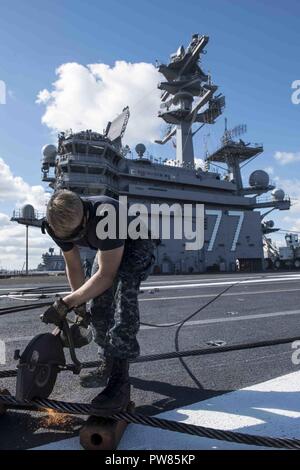 NORFOLK, Va (Oct. 2, 2017) Aviation Boatswain’s Mate (Equipment) Airman Rusty Knight uses a circular saw to break down an arresting cable on the flight deck aboard the aircraft carrier USS George H.W. Bush (CVN 77). The ship is in port Norfolk, Virginia, conducting routine maintenance after a seven-month deployment in support of maritime security operations and theater security cooperation efforts in the U.S. 5th and 6th Fleet areas of responsibility. Stock Photo