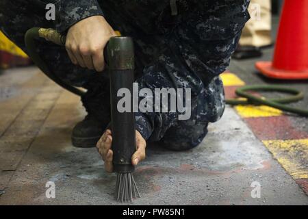 NORFOLK, Va. (Sept. 25, 2017) Airman Grant Made uses a needle gun to strip the hangar bay deck aboard the aircraft carrier USS George H.W. Bush (CVN 77). The ship is in port in Norfolk, Virginia conducting routine maintenance after a seven-month deployment in support of maritime security operations and theater security cooperation efforts in the U.S. 5th and 6th Fleet areas of responsibility. Stock Photo