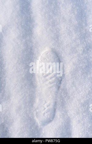 Human foot print in shoes on white freshly fallen snow. Stock Photo