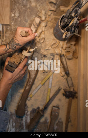 Female hands work with a wooden product. Tools for working with a tree lies on a table with sawdust. View from above Stock Photo