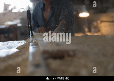 The carpenter saws the wooden board on the machine in the workshop. Concept Stock Photo