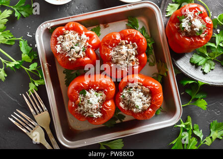 Tasty stuffed red peppers with minced meat, rice, onion, parmesan cheese in pan on black stone background. Top view, flat lay Stock Photo