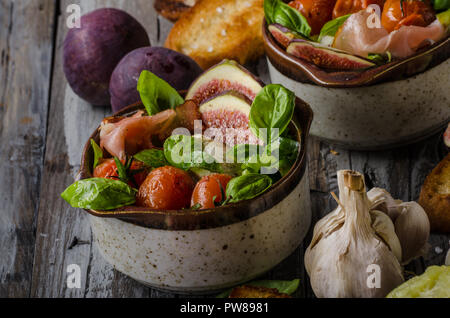 Herby salad, fresh figs, baked tomatoes, basil in and fresh roasted garlic toasts Stock Photo