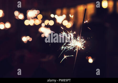 Beautiful sparkler firework flame on black background. Bright bengal lights spark in the darkness. Night firework flick. Blurred lights of firework. B Stock Photo