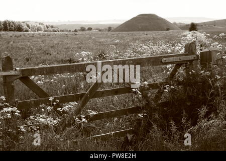 Black and white  image of Silbury Hill  prehistoric artificial chalk mound .in a field behind wooden five bar gate near Avebury Wiltshire England UK Stock Photo