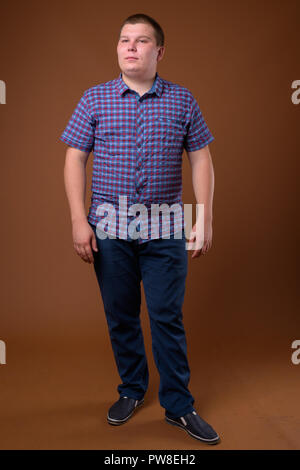 Studio shot of overweight young man against brown background Stock Photo