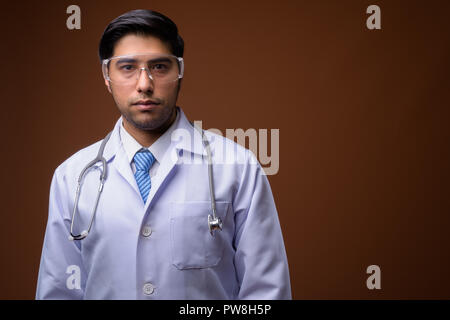 Young handsome Iranian man doctor wearing protective glasses aga Stock Photo