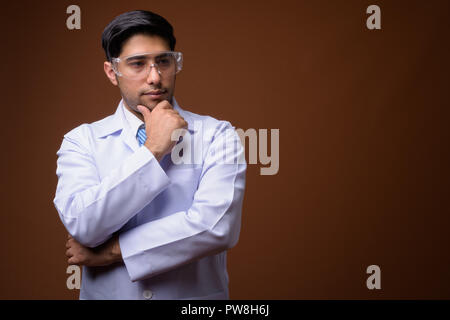Young handsome Iranian man doctor wearing protective glasses aga Stock Photo