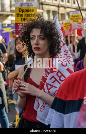 London, UK. 13th October 2018.   A woman in the crowd with a Baker's Union (BFAWU) flag at the rally in London to oppose racism  and fascism close to where the racist, Islamophobic DFLA were ending their march on Whitehall bringing together various groups to stand in solidarity with the communities the DFLA attacks. The event was organised by Stand Up To Racism and Unite Against Fascism. Peter Marshall/Alamy Live News Stock Photo