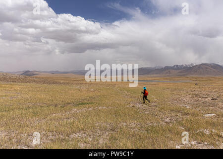 Trekker in Tajik Wakhan with Afghan Great Pamir in background on trek from Keng Shiber to Kara Jilga, Pamir Mountains, Gorno-Badakhshan, Tajikistan. Stock Photo