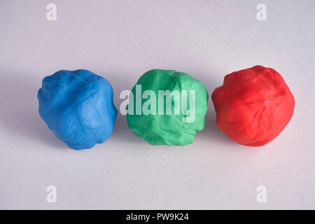 Blue, red and green moulds of plasticine on a grey surface. Close up. Stock Photo