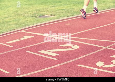 Sportsman legs in running shoes on the stadium red tartan track. Stock Photo