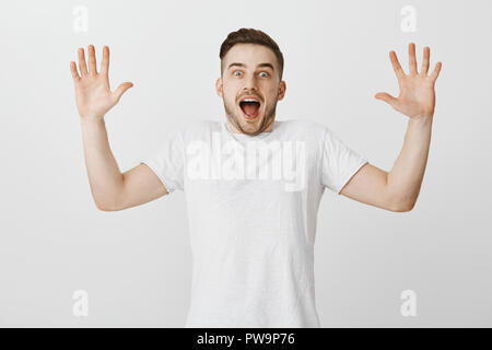 Studio shot of excited enthusiastic handsome male with bristle raising palms hight and shouting from happiness and amazement being surprised with awesome news reacting to fascinating story Stock Photo