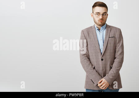 Intense worried european male employee feeling awkward and confused making mistake being scolded by boss feeling discomfort being in uncomfortable situation holding hands near pants and gazing aside Stock Photo