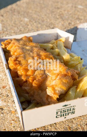 A portion of cod and chips served in a cardboard box on the seafront near the Weymouth Pleasure Pier. Dorset England UK GB. Stock Photo