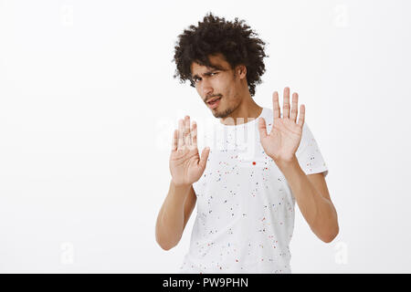 No mate stop. Displeased careless intense male model with afro hairstyle, rejecting annoying offer with raised palms, frowning and turning away from dislike, refusing to come with drunk friend Stock Photo