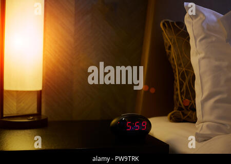 Alarm clock near the bed in bedroom Stock Photo