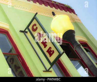 Tight crop with blue sky and clouds building wall cafe sign slanted view yellow lamppost Stock Photo