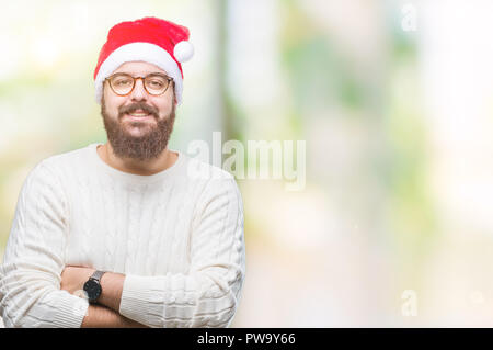 Young caucasian man wearing christmas hat and glasses over isolated background happy face smiling with crossed arms looking at the camera. Positive pe Stock Photo