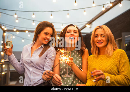Group of partying girls with flutes with sparkling wine and bengal fire having fun on the party Stock Photo