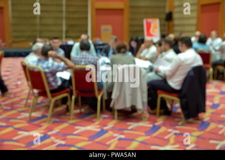 Blurred photo of audience group attending in conference meeting room. Group of business people attending press conference or presentation. Stock Photo