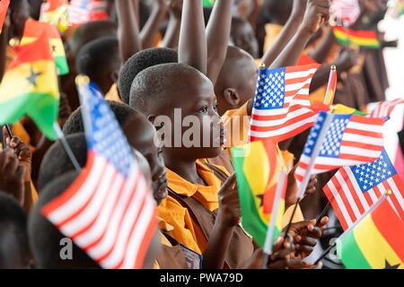 Young Ghanian school children wave flags to greet U.S First Lady Melania Trump during a welcoming ceremony on arrival to Kotoka International Airport October 2, 2018 in Accra, Ghana. This is the first solo international trip by the First Lady. Stock Photo