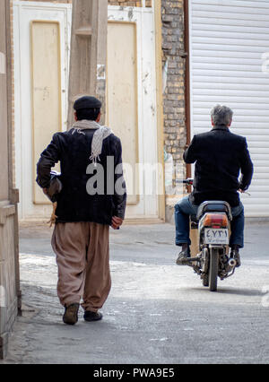 Yazd, Iran - March 7, 2017 : daily scene in a narrow alley of Old Town. Man riding a motorbike. Man holding a chicken Stock Photo