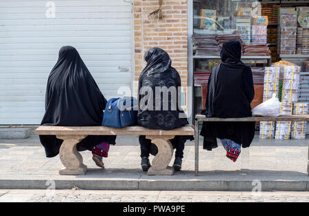 Yazd, Iran - March 7, 2017 : three women with islamic black chador sitting on benches Stock Photo