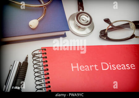 Titled red book Heart Disease along with medical equipment, conceptual image Stock Photo