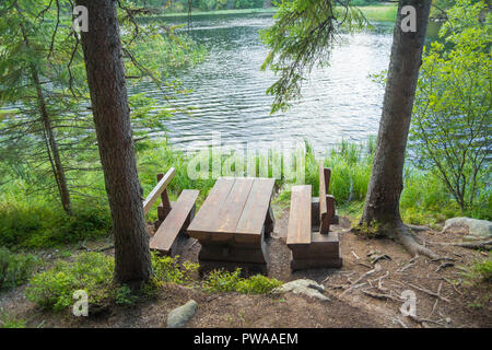 picnic table seating in forest near lake Stock Photo