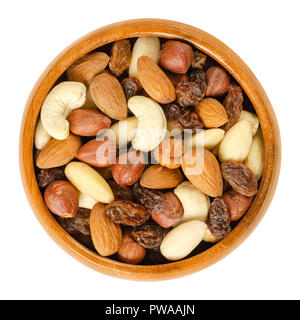 Nuts and raisins in wooden bowl. Snack mix of dried almonds, hazelnuts, cashews and raisins. Trail mix. Edible, raw, organic and vegan. Stock Photo
