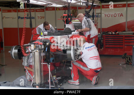 F1 mechanics at work on a Toyota F1 race car in the pit lane workshop ...