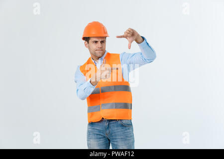 Young handsome architec man with long hair wearing safety helmet over isolated background smiling making frame with hands and fingers with happy face. Creativity and photography concept Stock Photo