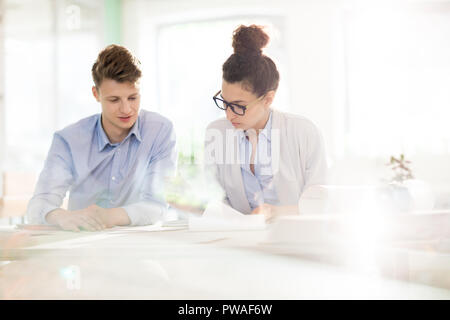 Two young analysts looking through documents and discussing data at working meeting Stock Photo