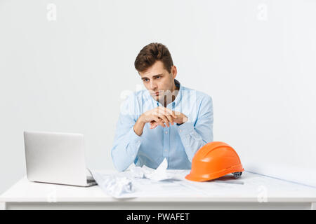 young attractive engineer man feeling tired at work place Stock Photo