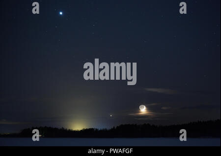 Conjuction of Jupiter, Venus and Moon on night sky above snowy winter landscape. Conjunction date 25. 3. 2012. Stock Photo