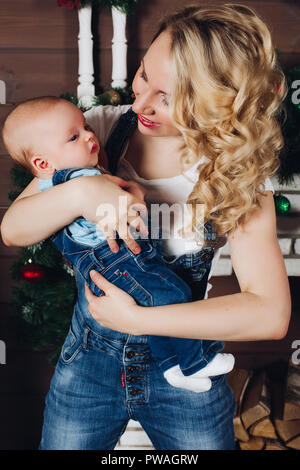Boy with beautiful blonde mom embracing in decorated studio for Christmas. Stock Photo