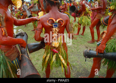 Colourfully dressed and face painted men with drums dancing as part of a Sing Sing in Madang, Papua New Guinea. Stock Photo