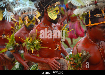 Colourfully dressed and face painted men with drums dancing as part of a Sing Sing in Madang, Papua New Guinea. Stock Photo