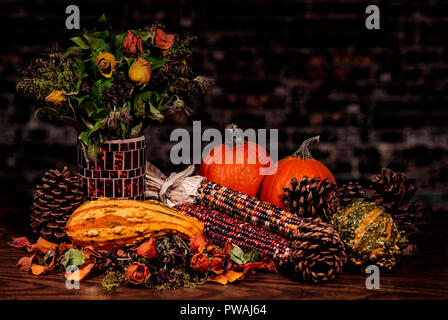 Beautiful Earthy colors in a fall still life with pumpkins, pine cones, Gourds, squash and Indian Corn on a bed of dried leaves and rose petals Stock Photo