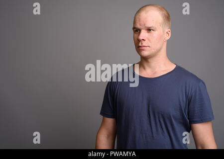 Bald man wearing blue shirt against gray background Stock Photo