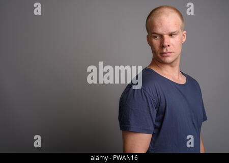 Bald man wearing blue shirt against gray background Stock Photo