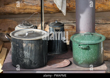 Yukon Territory, Alaska. Close up of pots and pans in an old iron cooking stove placed in the outside of a cabin. Stock Photo