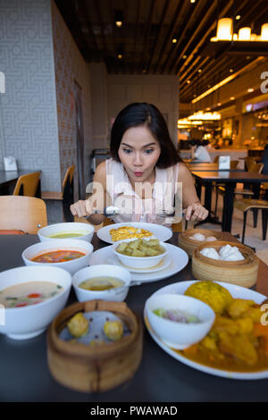 Young beautiful Asian woman eating at restaurant with many choices of food