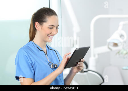 Happy dentist consulting online information in a tablet in a consultation Stock Photo